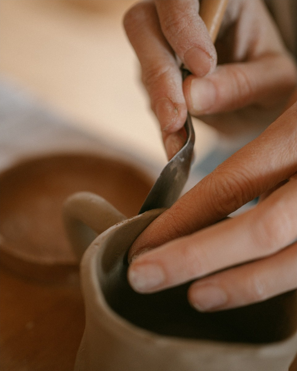 A potter shaping a clay cup by hand